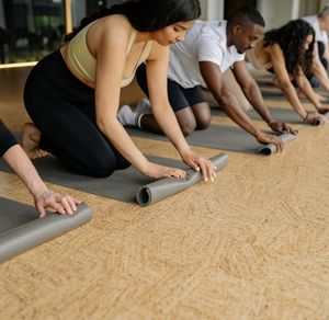 An empty yoga mat rolled out on a clean wooden floor.